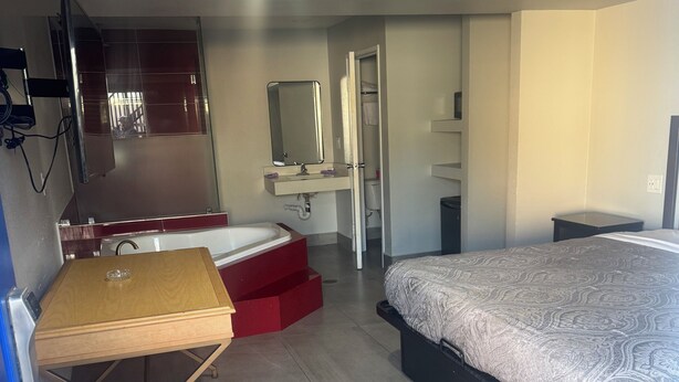 Un dormitorio con cama, escritorio, espejo, armario y baño.