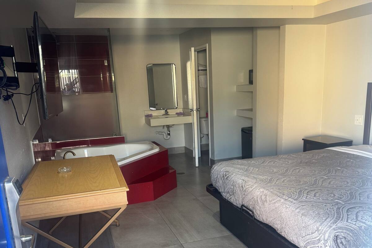 A bedroom with a bed, a desk, a mirror, a wardrobe, and a bathroom.