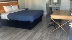 Una habitación de hotel con cama, escritorio, silla, televisor y baño.