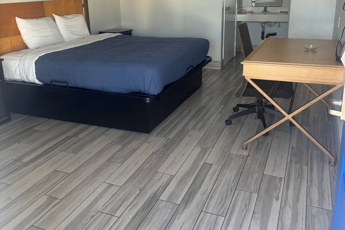 A hotel room with a bed, a desk, a chair, a television, and a bathroom.