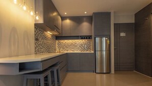 Een moderne keuken met een roestvrijstalen koelkast, een betegelde spatwand en een bar met krukken.
