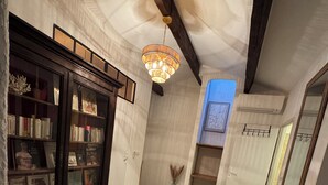 A hallway with a wooden bookcase, a patterned rug, and a hanging light fixture. - Charming sea view apartment "Maison Leya (Saintes-Maries-de-la-Mer)