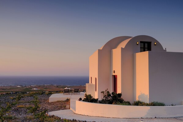 A modern building with a curved roof, a small porch, and a view of the sea. - Deluxe Villa with Plunge Pool in Oia (Oia)