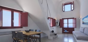 A modern interior with a dining area, a sofa, and a staircase. - Deluxe Villa with Plunge Pool in Oia (Oia)