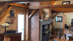 Un loft espacioso con chimenea, vigas de madera y un ventanal de vitral.