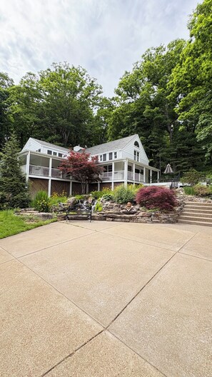 A large white building with a covered porch and a stone staircase leading to a deck.