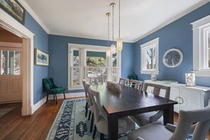 Een eetkamer met een houten tafel, stoelen en hangende pendantlampen.