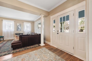 A spacious living room with a dark brown sofa, a patterned rug, and a white door with glass panels. - 12 South Sanctuary | Azure Pool & Private Cabana (Nashville)