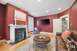 A living room with a fireplace, a television mounted on the wall, a sofa, and a coffee table. - 12 South Sanctuary | Azure Pool & Private Cabana (Nashville)