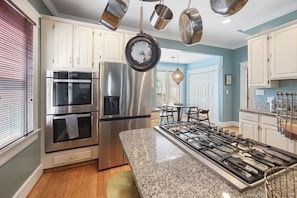 A modern kitchen with stainless steel appliances, a granite countertop, and a dining area with a table and chairs. - 12 South Sanctuary | Azure Pool & Private Cabana (Nashville)
