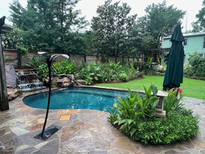A backyard with a swimming pool, a waterfall feature, and a stone patio. - 12 South Sanctuary | Azure Pool & Private Cabana (Nashville)