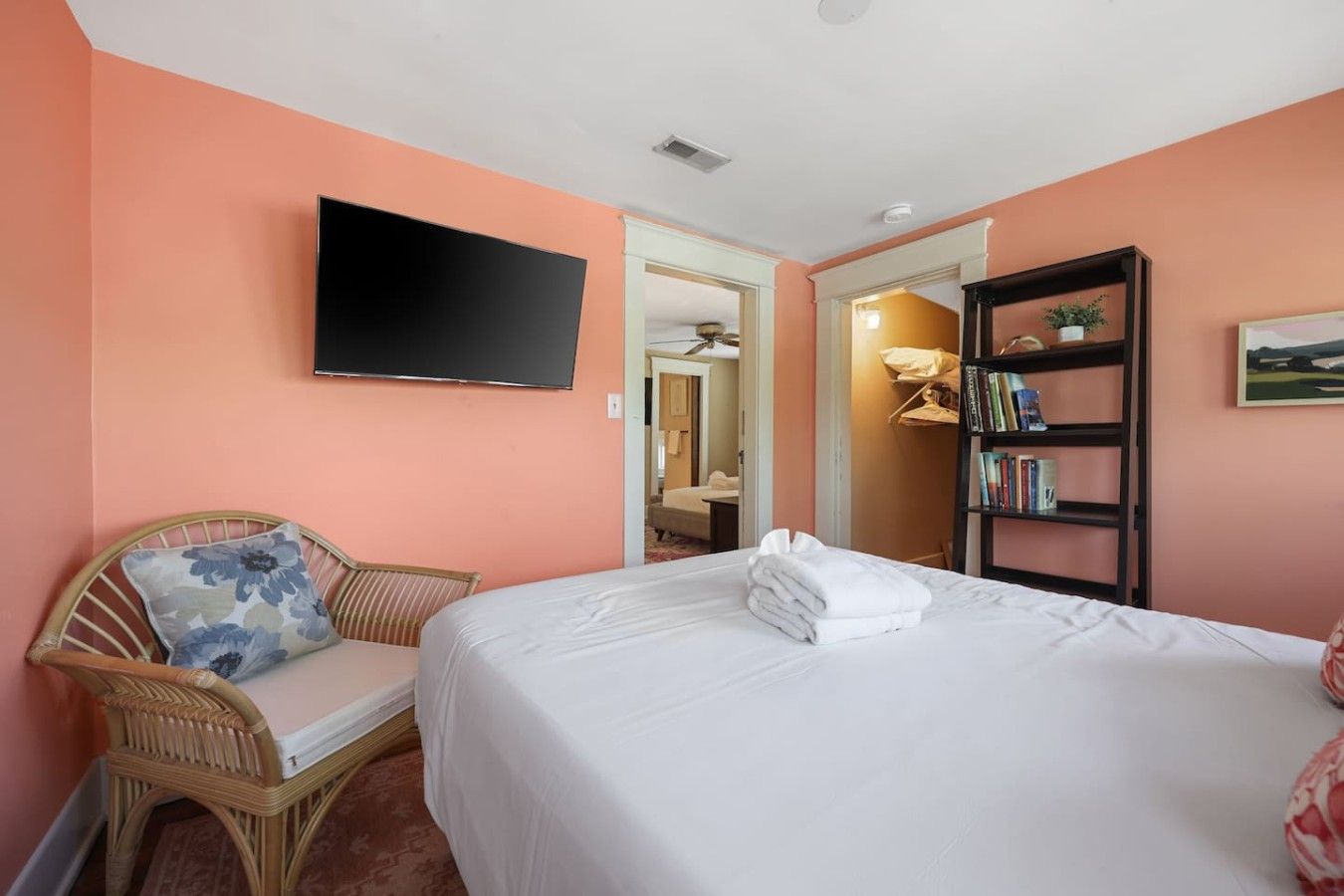A hotel room with a bed, a television, a bookshelf, and a chair.