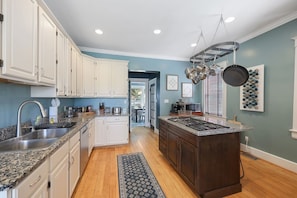 A modern kitchen with white cabinets, granite countertops, and a central island with a stove. - 12 South Sanctuary | Azure Pool & Private Cabana (Nashville)