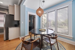 A dining area with a round table, chairs, and a hanging light fixture. - 12 South Sanctuary | Azure Pool & Private Cabana (Nashville)