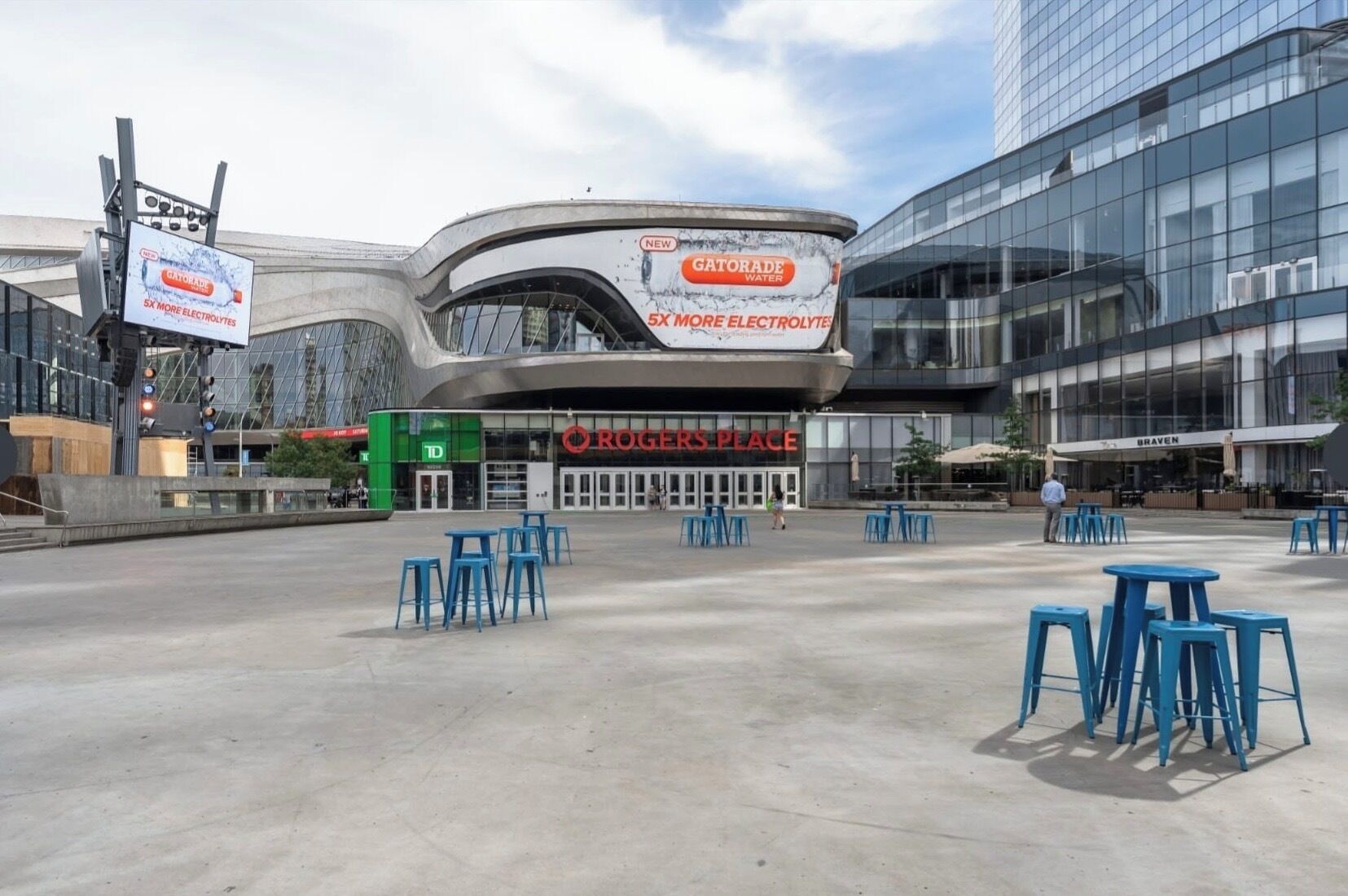 Un edificio moderno con fachada curva, un cartel grande de Gatorade y un área de estar al aire libre.