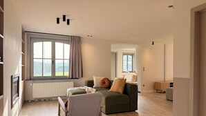 Een moderne woonkamer met een bank, een stoel, een radiator en een raam met gordijnen.