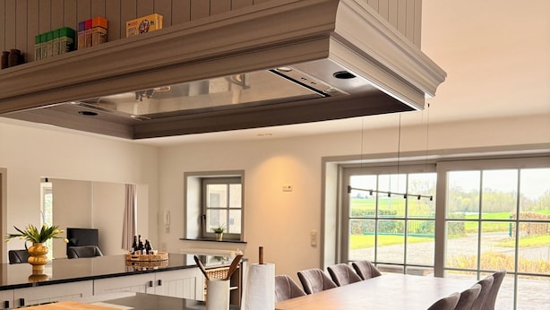 Een moderne keuken met een centraal eiland, inbouwkeuken en een groot raam met uitzicht op de omgeving.