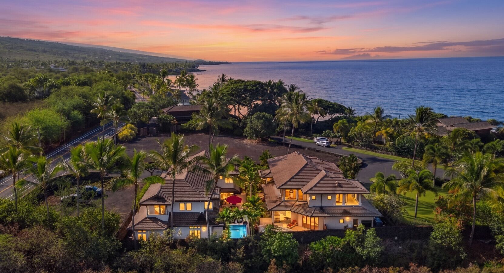 A large, multi-story house with a swimming pool, surrounded by palm trees and a view of the ocean.