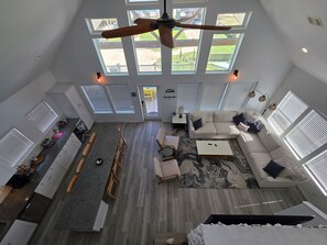 Ein großzügiger Wohnbereich mit hoher Decke, Oberlichtern, Deckenventilator und Blick auf den Garten.