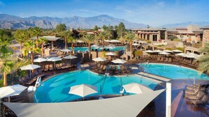 Un complexe hôtelier doté de plusieurs piscines, de chaises longues, de parasols et offrant une vue imprenable sur les montagnes.