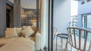 A modern living room with a sofa, a glass door leading to a balcony, and a view of the cityscape. - Famous City Gate Walk Beach 4km Patong C142 (Kamala)