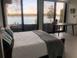 Una camera da letto con un letto, una scrivania e vista su un lago.