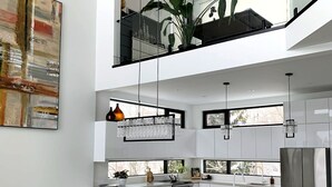 Una cocina moderna con armarios blancos, una mesa de comedor de madera y sillas negras.