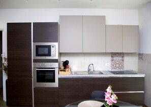 A modern kitchen with built-in appliances, a sink, and decorative tiles. - One Bedroom Apartment with Terrace (Bari)