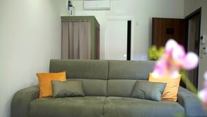 Een woonkamer met een bank, een deur en een wandairconditioner.