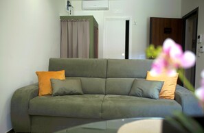 A living room with a sofa, a door, and a wall-mounted air conditioner. - One Bedroom Apartment with Terrace (Bari)