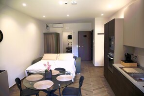 A hotel room with a bed, a dining table with chairs, a kitchenette, and a bathroom visible in the background. - One Bedroom Apartment with Terrace (Bari)