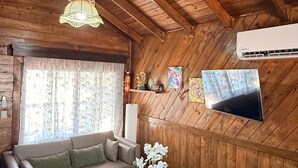A wooden interior with a sofa, a round coffee table, a hanging light fixture, and a mounted TV. - Luxury cottage in front of the sea and lagoon of miami Tela (TELA)