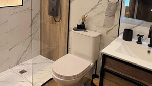 Ein modernes Badezimmer mit einer Duschkabine, einer Toilette und einem Waschtisch mit Spiegel.