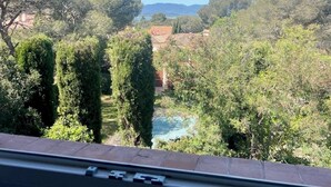 A view from inside a building, looking out at a landscape with trees and a distant body of water.