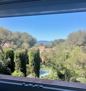 Blick aus einem Gebäude auf eine Landschaft mit Bäumen und weiter Wasserfläche.