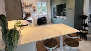 A modern kitchen with a marble island, bar stools, and a built-in oven.