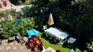 A patio area with a table and chairs, a potted plant, and a view of a pool.