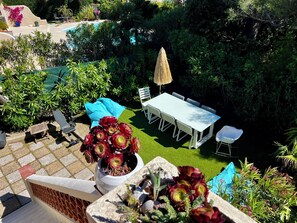 Eine Terrasse mit Tisch und Stühlen, einem Blumentopf und Blick auf einen Pool.