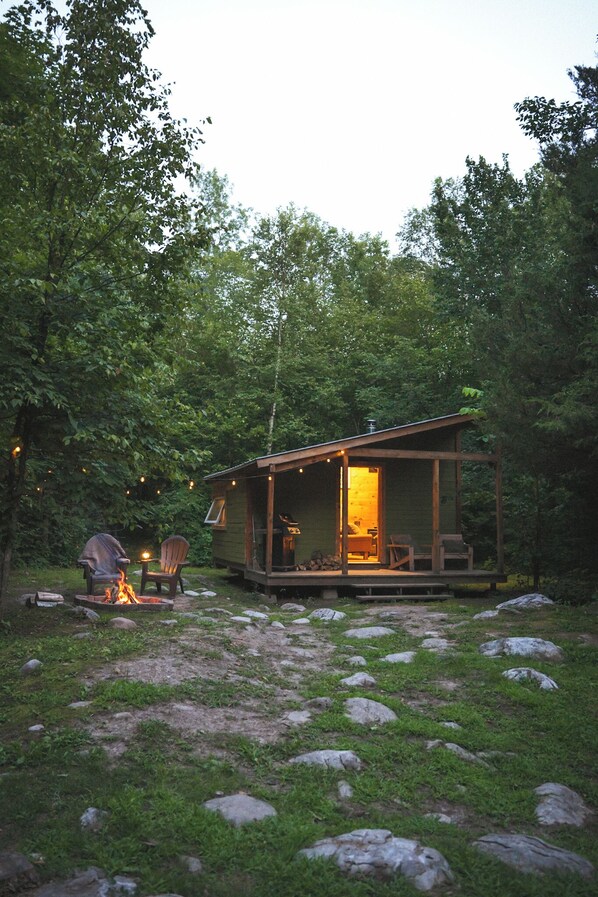 Eine Hütte mit Veranda, Feuerstelle und Sitzgelegenheiten im Freien.