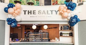 Ein Schaufenster mit der Beschriftung 'THE SALTY', eine Auslage mit Backwaren und Regale mit Kaffee-Produkten.