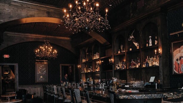 A bar area with high chairs, a bar counter, and shelves of bottles. - Steps to Bishop Arts, Private Yard + Pet-Friendly (Dallas)