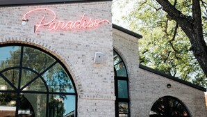 A building with a neon sign reading 'Paradiso,' large arched windows, and a brick facade. - Steps to Bishop Arts, Private Yard + Pet-Friendly (Dallas)