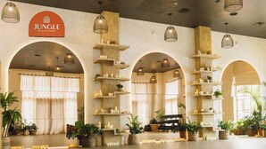 A spacious lobby with a large sign for Jungle Studio Fitness, multiple arches, and various potted plants. - Steps to Bishop Arts, Private Yard + Pet-Friendly (Dallas)