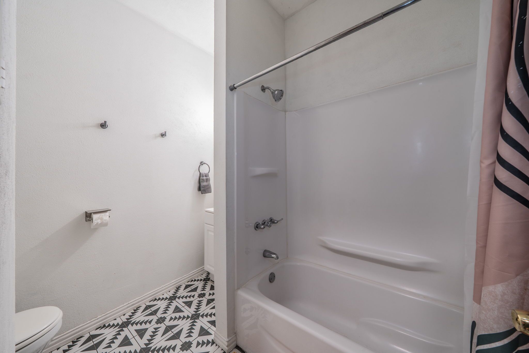 A bathroom with a toilet, a shower with a glass door, and a patterned floor.