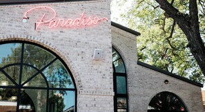 Ein Gebäude mit einer Neonreklame mit der Aufschrift 'Paradiso', großen Bogenfenstern und einer Ziegel-Fassade.