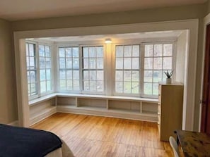 Una habitación con ventanal saliente, suelo de madera y un banco empotrado.