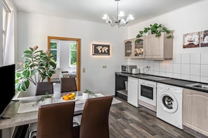 A modern kitchen with a dining area, a washing machine, and a large window.
