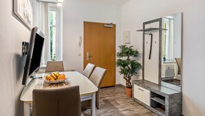Une chambre d’hôtel moderne dotée d’un coin repas, d’un téléviseur à écran plat, d’une plante en pot et d’un grand miroir.