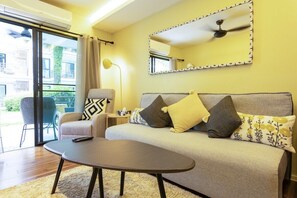 Ein Wohnzimmer mit einer Couch, einem Couchtisch, einem Sessel, einer Lampe und einem Deckenventilator.