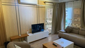 Un soggiorno con televisore, divano e tavolino.